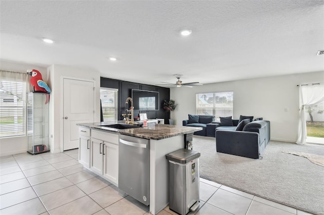 kitchen featuring stainless steel dishwasher, a sink, white cabinetry, an island with sink, and light carpet