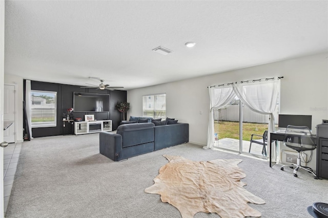 carpeted living room with ceiling fan and a desk