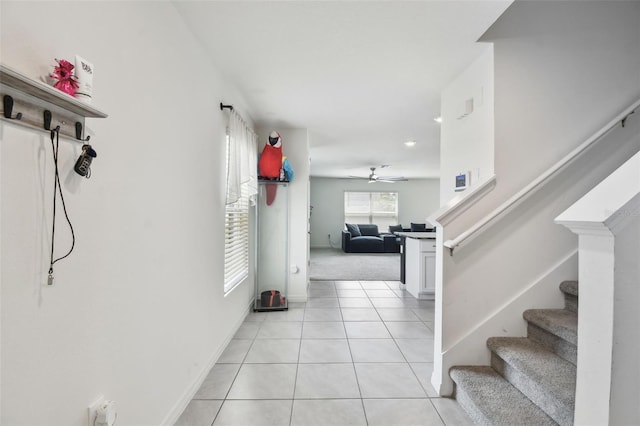 hall featuring stairway, light tile patterned floors, and baseboards