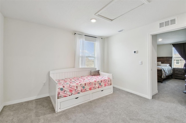 carpeted bedroom featuring baseboards and attic access