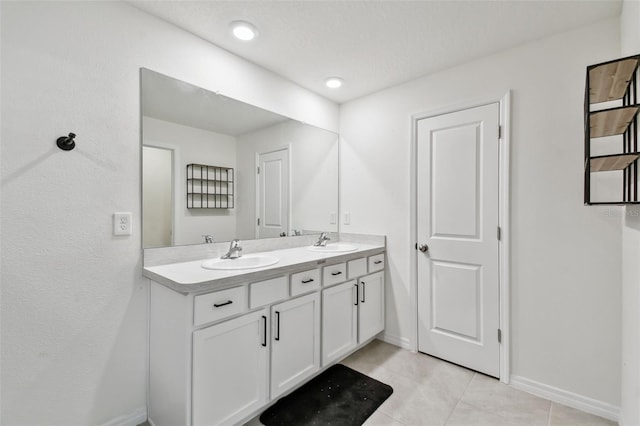full bath with tile patterned flooring, double vanity, and baseboards