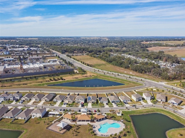 aerial view of property's location with a large body of water, a pool, and nearby suburban area
