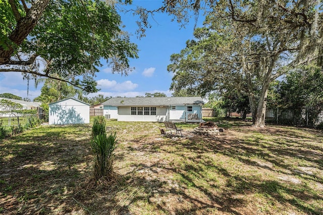 12019 106th Ct, Largo, FL 33778 - rear view of house with a fire pit, a fenced backyard, and an outbuilding