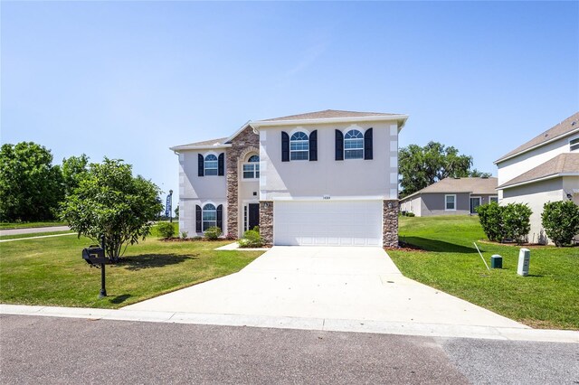 14384 NW 160th Ln, Alachua, FL 32615 - view of front of home with stone siding, a garage, a front lawn, stucco siding, and driveway