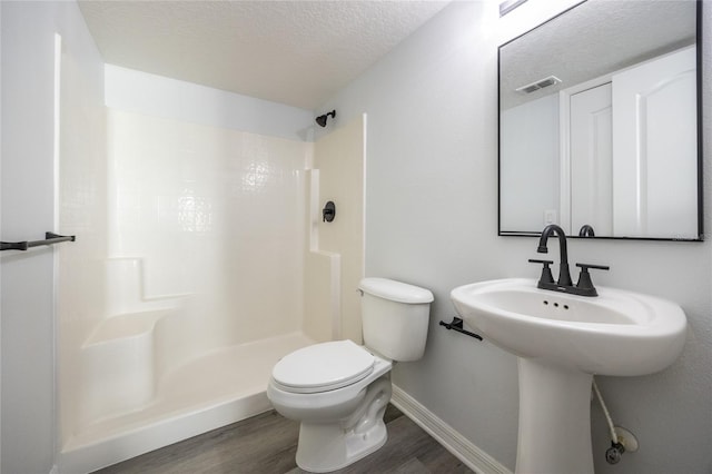 14384 NW 160th Ln, Alachua, FL 32615 - bathroom featuring wood finished floors, a shower, toilet, a textured ceiling, and baseboards