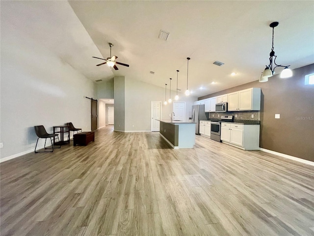 6376 SW 117th Street Rd, Ocala, FL 34476 - kitchen featuring appliances with stainless steel finishes, open floor plan, a barn door, light wood-type flooring, and white cabinetry