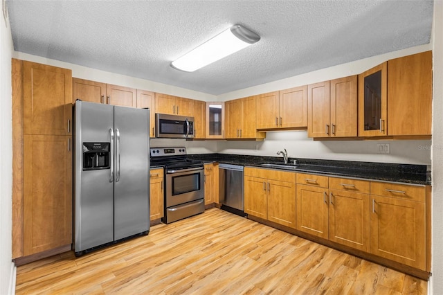 10511 Waterview Ct Unit 10511, Tampa, FL 33615 - kitchen featuring stainless steel appliances, a sink, light wood-type flooring, a textured ceiling, and glass insert cabinets