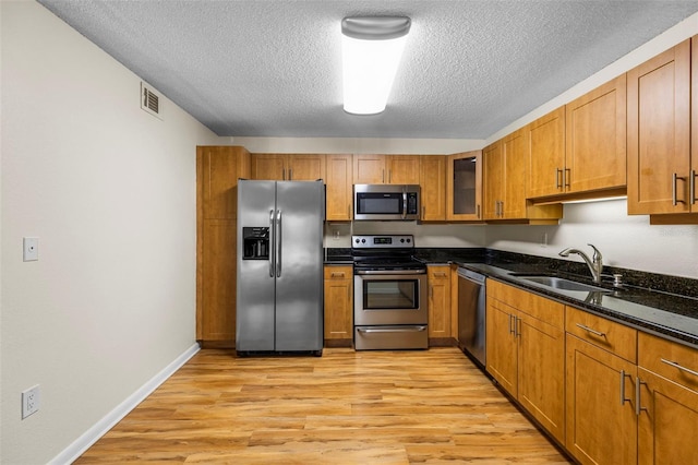 10511 Waterview Ct Unit 10511, Tampa, FL 33615 - kitchen featuring stainless steel appliances, a sink, a textured ceiling, brown cabinetry, and light wood finished floors