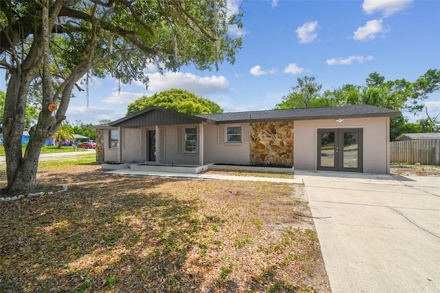 view of front of property with french doors, stone siding, stucco siding, and concrete driveway