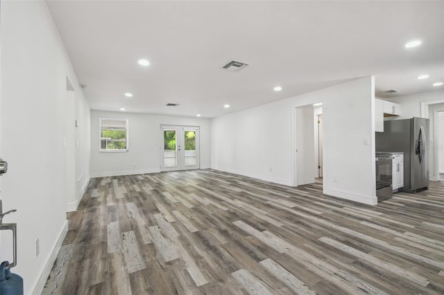 unfurnished living room featuring wood finished floors, french doors, recessed lighting, and baseboards