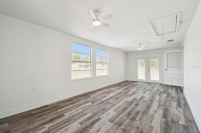unfurnished room featuring attic access, healthy amount of natural light, and wood finished floors