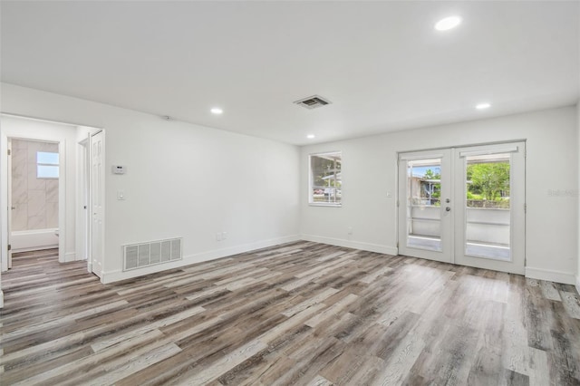 unfurnished room with plenty of natural light, wood finished floors, recessed lighting, and baseboards
