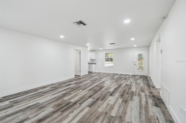 unfurnished living room with recessed lighting, wood finished floors, and baseboards