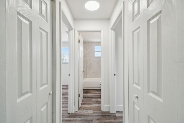hall featuring dark wood-style flooring and baseboards