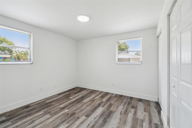 unfurnished bedroom with wood finished floors, baseboards, and a closet