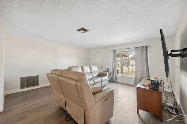 living room with wood finished floors, a textured ceiling, and baseboards