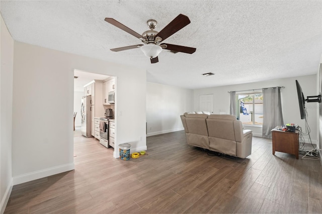 living area with ceiling fan, baseboards, wood finished floors, and a textured ceiling
