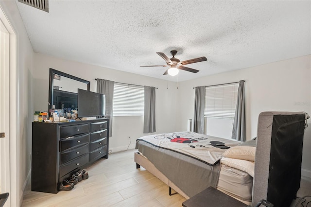 bedroom featuring light wood-style flooring, a textured ceiling, and ceiling fan