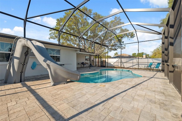 view of swimming pool with a water slide, a patio area, glass enclosure, and a fenced backyard