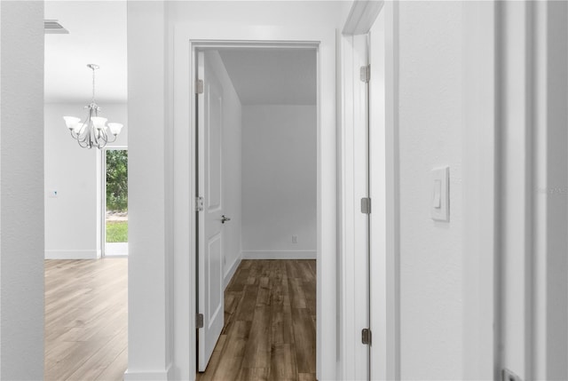 16247 Little Auk Rd, Weeki Wachee, FL 34614 - hall featuring wood finished floors, a chandelier, and baseboards