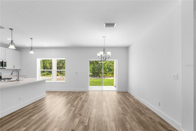 16247 Little Auk Rd, Weeki Wachee, FL 34614 - unfurnished living room featuring light wood-style floors, a sink, baseboards, and a chandelier