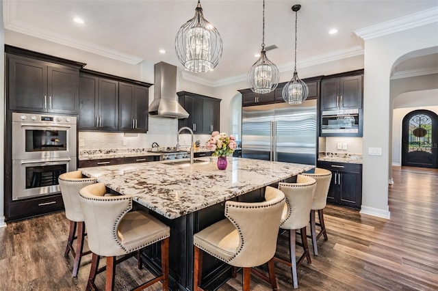17724 Daisy Farm Dr, Lutz, FL 33559 - kitchen featuring stainless steel appliances, wall chimney range hood, arched walkways, a chandelier, and dark wood-style flooring