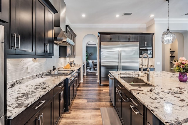 17724 Daisy Farm Dr, Lutz, FL 33559 - kitchen featuring wall chimney range hood, arched walkways, light stone countertops, wood finished floors, and ornamental molding