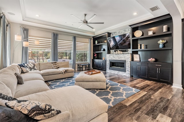 17724 Daisy Farm Dr, Lutz, FL 33559 - living room with ceiling fan, dark wood finished floors, ornamental molding, a stone fireplace, and a tray ceiling