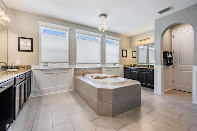 17724 Daisy Farm Dr, Lutz, FL 33559 - bathroom featuring a garden tub, vanity, a decorative wall, a wainscoted wall, and wood finished floors