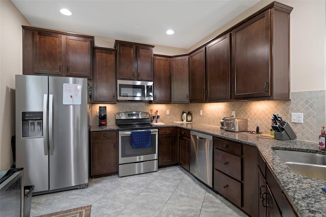 7001 Interbay Blvd Unit 242, Tampa, FL 33616 - kitchen featuring appliances with stainless steel finishes, dark brown cabinetry, dark stone countertops, backsplash, and recessed lighting