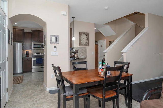7001 Interbay Blvd Unit 242, Tampa, FL 33616 - dining room featuring arched walkways, stairs, and baseboards