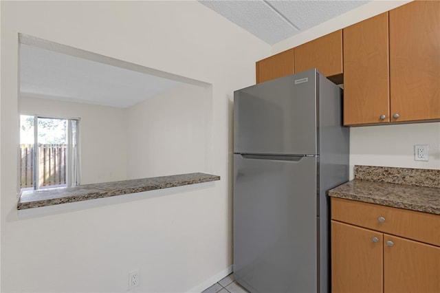 2820 Somerset Park Dr Unit 101, Tampa, FL 33613 - kitchen with freestanding refrigerator, tile patterned flooring, dark stone counters, and brown cabinets