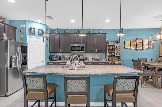 11684 Brighton Knoll Loop, Riverview, FL 33579 - kitchen with appliances with stainless steel finishes, dark brown cabinetry, a breakfast bar area, decorative backsplash, and recessed lighting