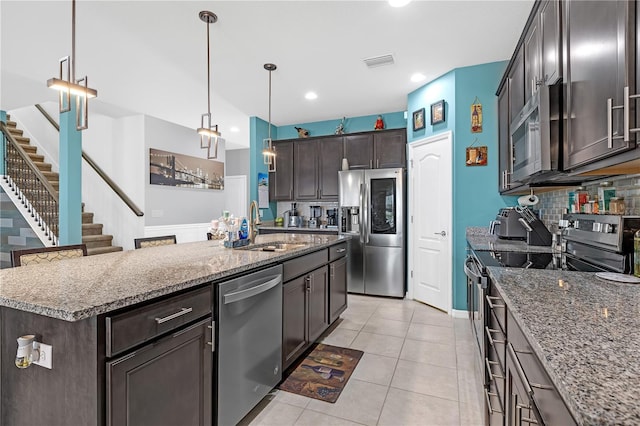 11684 Brighton Knoll Loop, Riverview, FL 33579 - kitchen featuring stainless steel appliances, dark brown cabinetry, a sink, backsplash, and dark stone counters