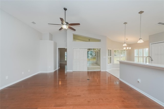 11741 Teapot Ct, Spring Hill, FL 34609 - unfurnished living room with ceiling fan, baseboards, a chandelier, wood finished floors, and lofted ceiling
