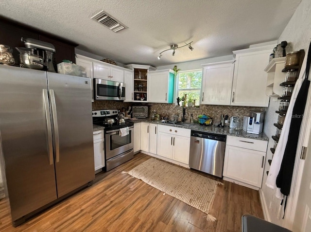 6741 4th Ave N, Saint Petersburg, FL 33710 - kitchen featuring appliances with stainless steel finishes, white cabinetry, a sink, backsplash, and wood finished floors