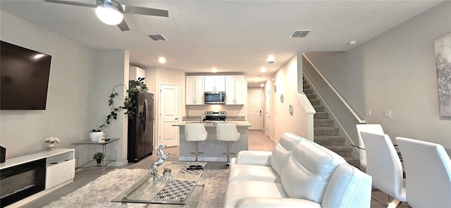 living room with a ceiling fan, stairs, light wood finished floors, and baseboards