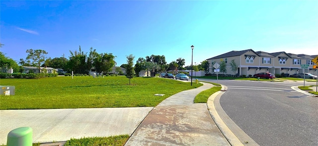 view of asphalt road with sidewalks, traffic signs, a residential view, street lighting, and curbs