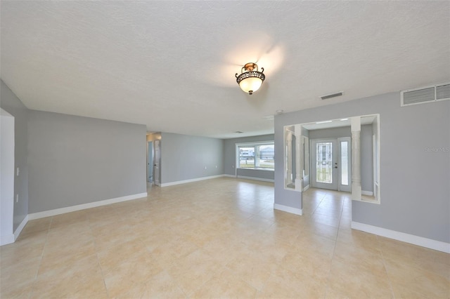 710 116th Ave, Treasure Island, FL 33706 - spare room featuring baseboards, a textured ceiling, and french doors