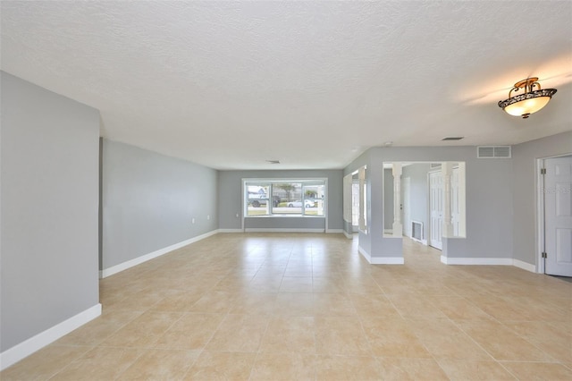 710 116th Ave, Treasure Island, FL 33706 - unfurnished living room with light tile patterned floors, baseboards, and a textured ceiling