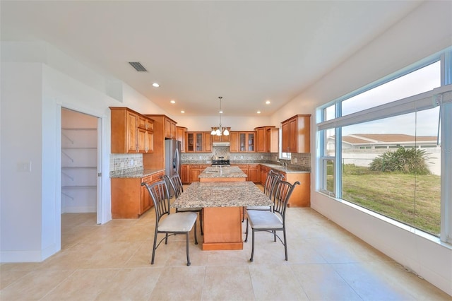 710 116th Ave, Treasure Island, FL 33706 - kitchen with brown cabinets, a center island, a chandelier, decorative backsplash, and recessed lighting