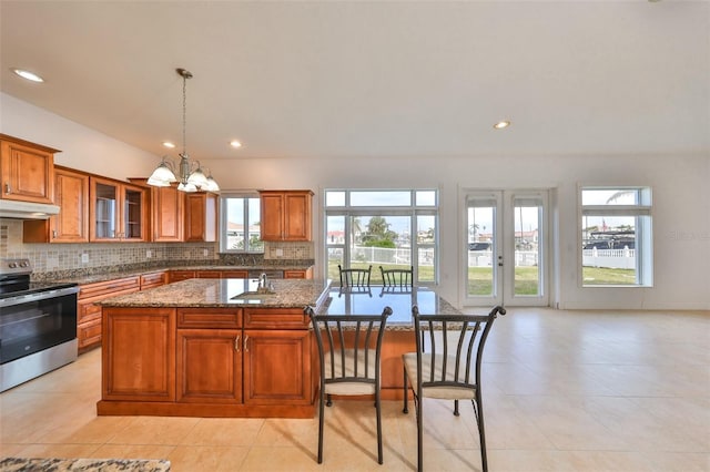 710 116th Ave, Treasure Island, FL 33706 - kitchen featuring electric range, under cabinet range hood, brown cabinets, a chandelier, and backsplash