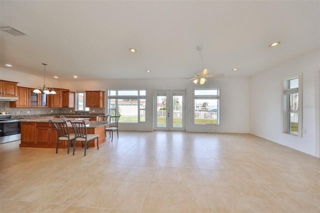710 116th Ave, Treasure Island, FL 33706 - kitchen featuring stainless steel range with electric stovetop, brown cabinets, under cabinet range hood, a breakfast bar area, and open floor plan
