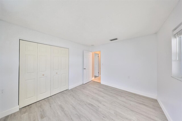 710 116th Ave, Treasure Island, FL 33706 - unfurnished bedroom featuring wood finished floors, baseboards, and a closet