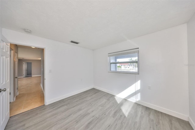 710 116th Ave, Treasure Island, FL 33706 - empty room featuring light wood-style floors, baseboards, a smoke detector, and a textured ceiling