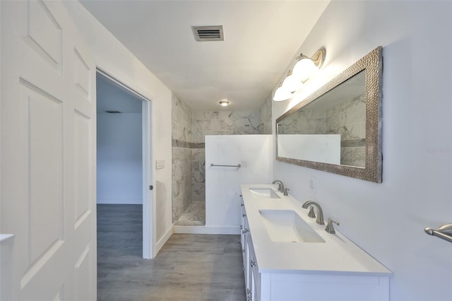 710 116th Ave, Treasure Island, FL 33706 - bathroom with double vanity, a walk in shower, wood finished floors, and baseboards
