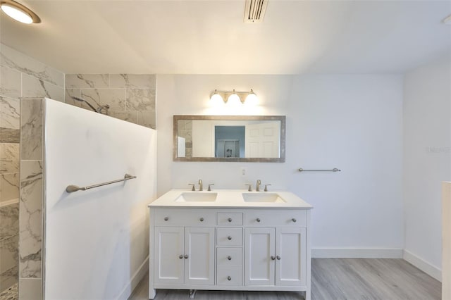 710 116th Ave, Treasure Island, FL 33706 - bathroom featuring double vanity, baseboards, a walk in shower, and wood finished floors