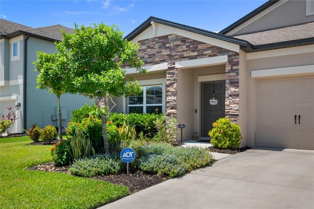 18428 Malinche Loop, Spring Hill, FL 34610 - view of exterior entry with stone siding, an attached garage, concrete driveway, and stucco siding