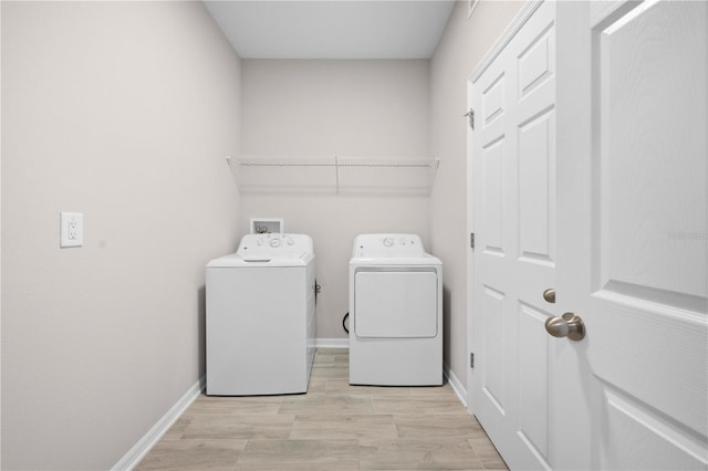 17618 Cortes Creek Blvd, Spring Hill, FL 34610 - laundry area with washer and clothes dryer, light wood-type flooring, and baseboards
