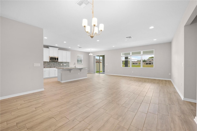 17618 Cortes Creek Blvd, Spring Hill, FL 34610 - unfurnished living room featuring a chandelier, recessed lighting, light wood-style flooring, baseboards, and a sink
